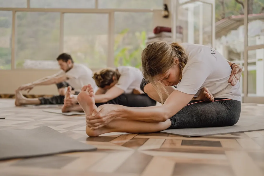 Group yoga class stretching in a bright wooden studio